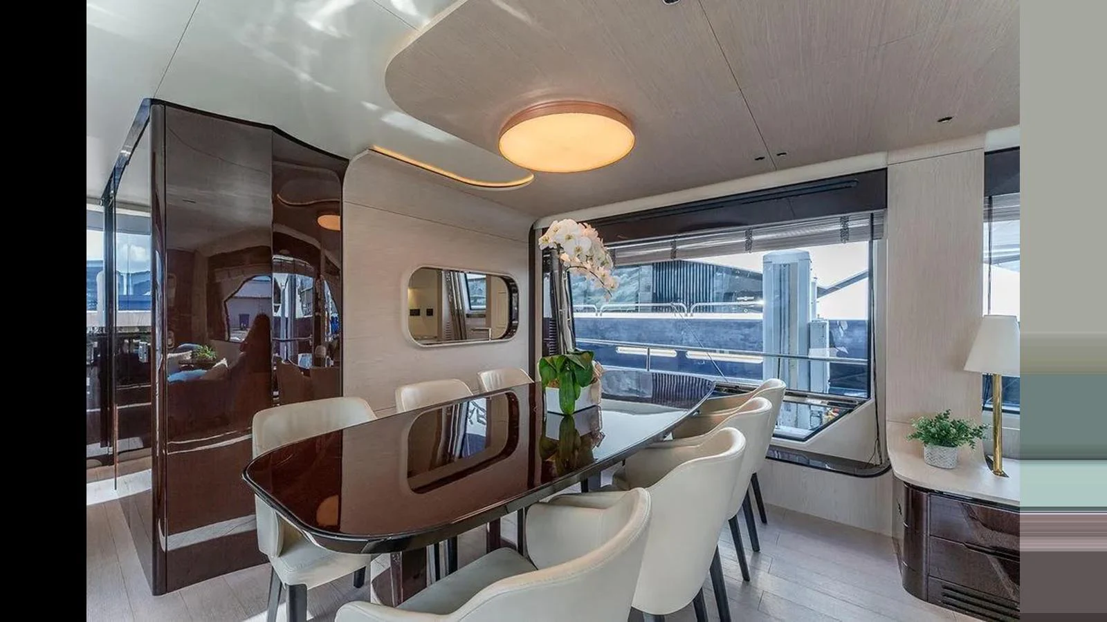 The yacht's dining area features a sleek table surrounded by plush chairs, with large windows offering a view of the marina. aboard 2022 AZIMUT GRANDE 25 METRI Yacht for Sale