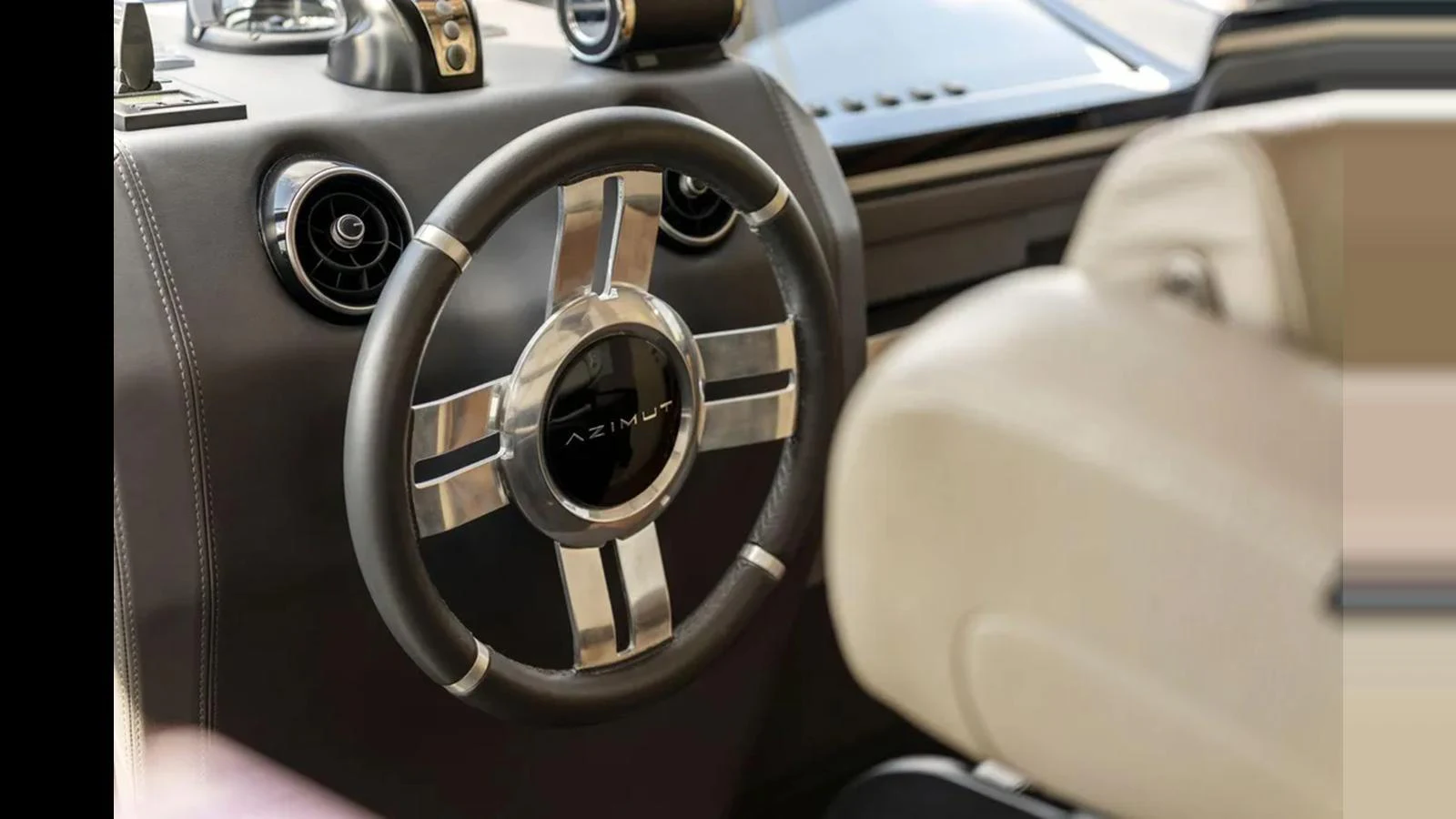 The image showcases the helm of the yacht with a modern steering wheel and control panel. aboard 2022 AZIMUT S10 Yacht for Sale