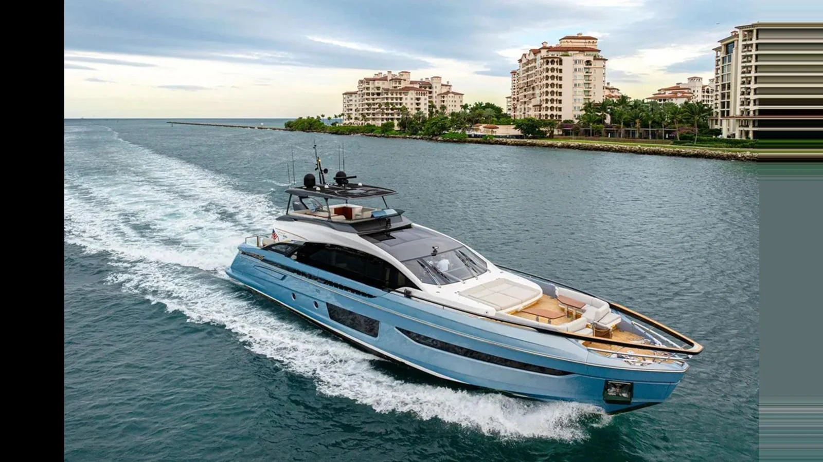A sleek yacht cruises through calm waters with a backdrop of luxury waterfront buildings. aboard 2022 AZIMUT S10 Yacht for Sale