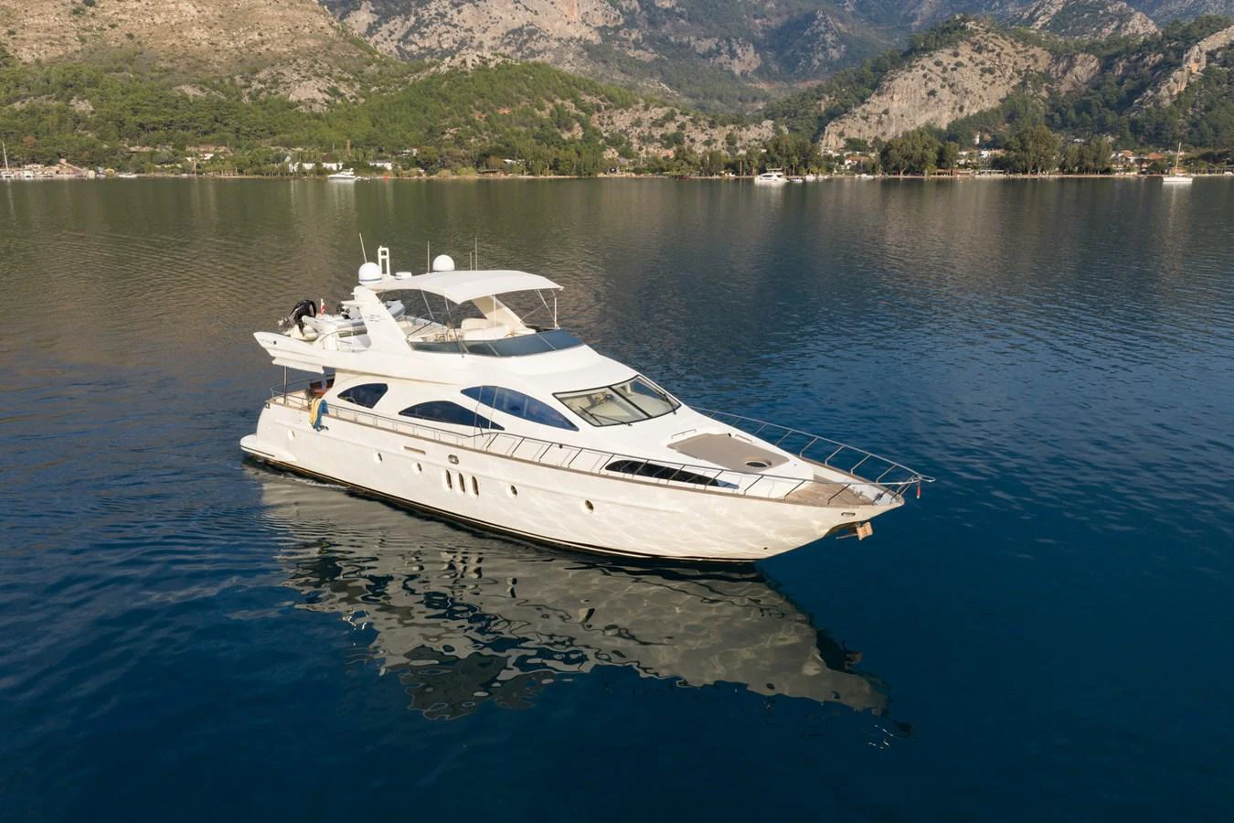 A sleek and elegant yacht cruising on calm waters with a scenic mountainous backdrop. aboard SENIOR S Yacht for Sale