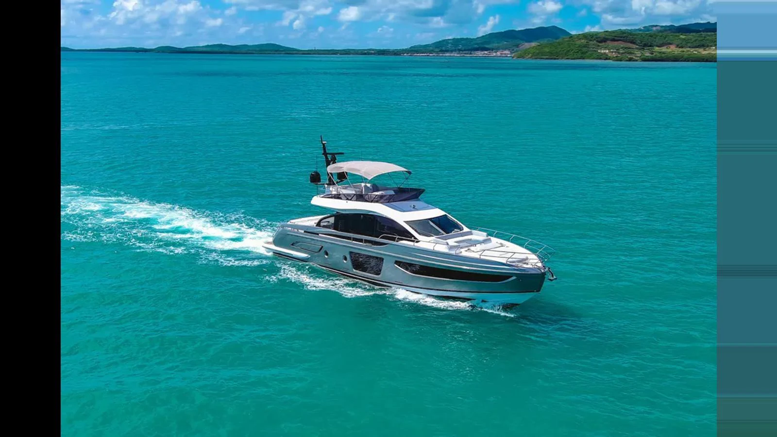 A sleek yacht cruises through turquoise waters with a scenic coastline in the background. aboard AZIMUT S7 Yacht for Sale