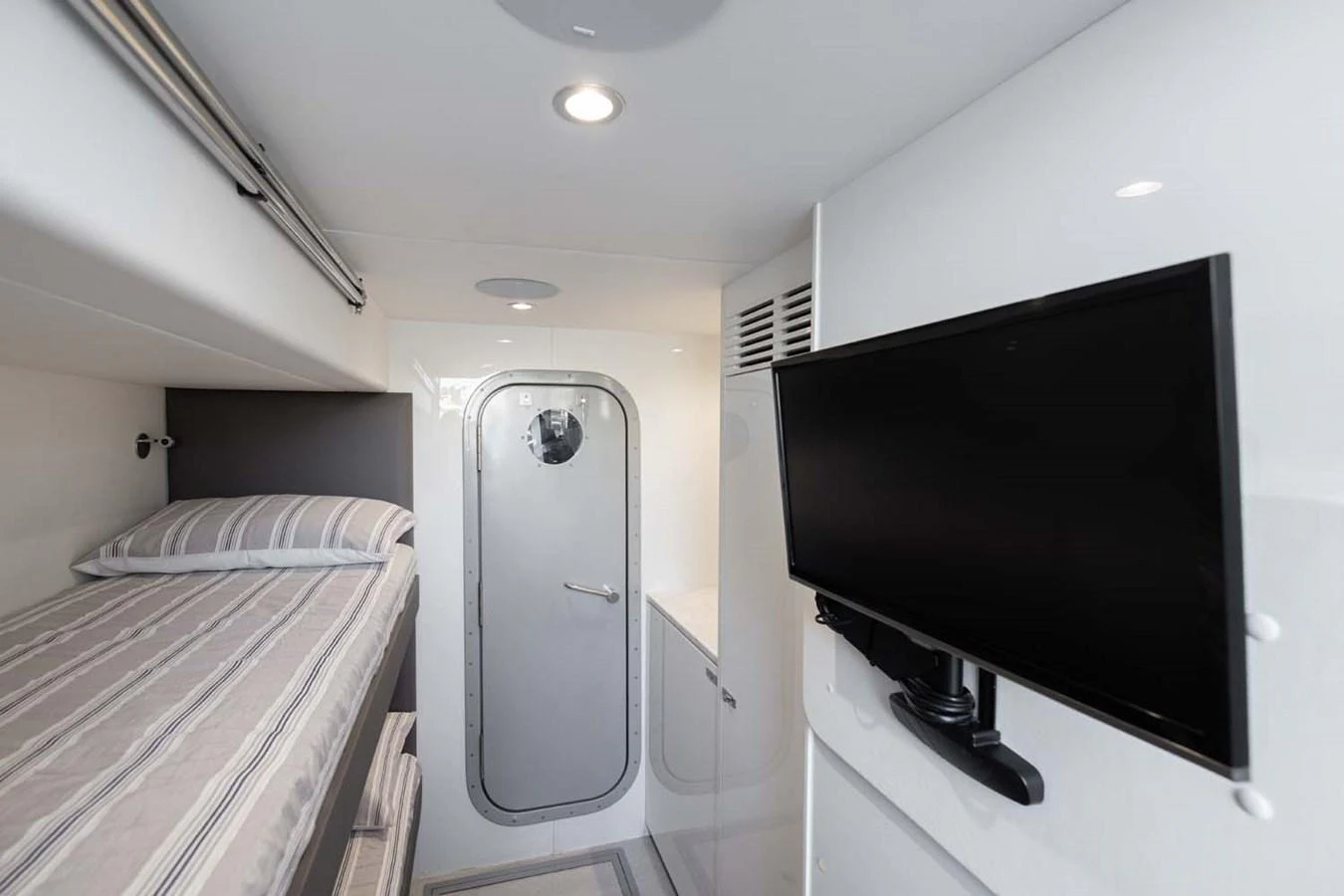 The cabin features a cozy bunk bed and a mounted flat-screen TV for comfort and entertainment. aboard CAMILLE Yacht for Sale