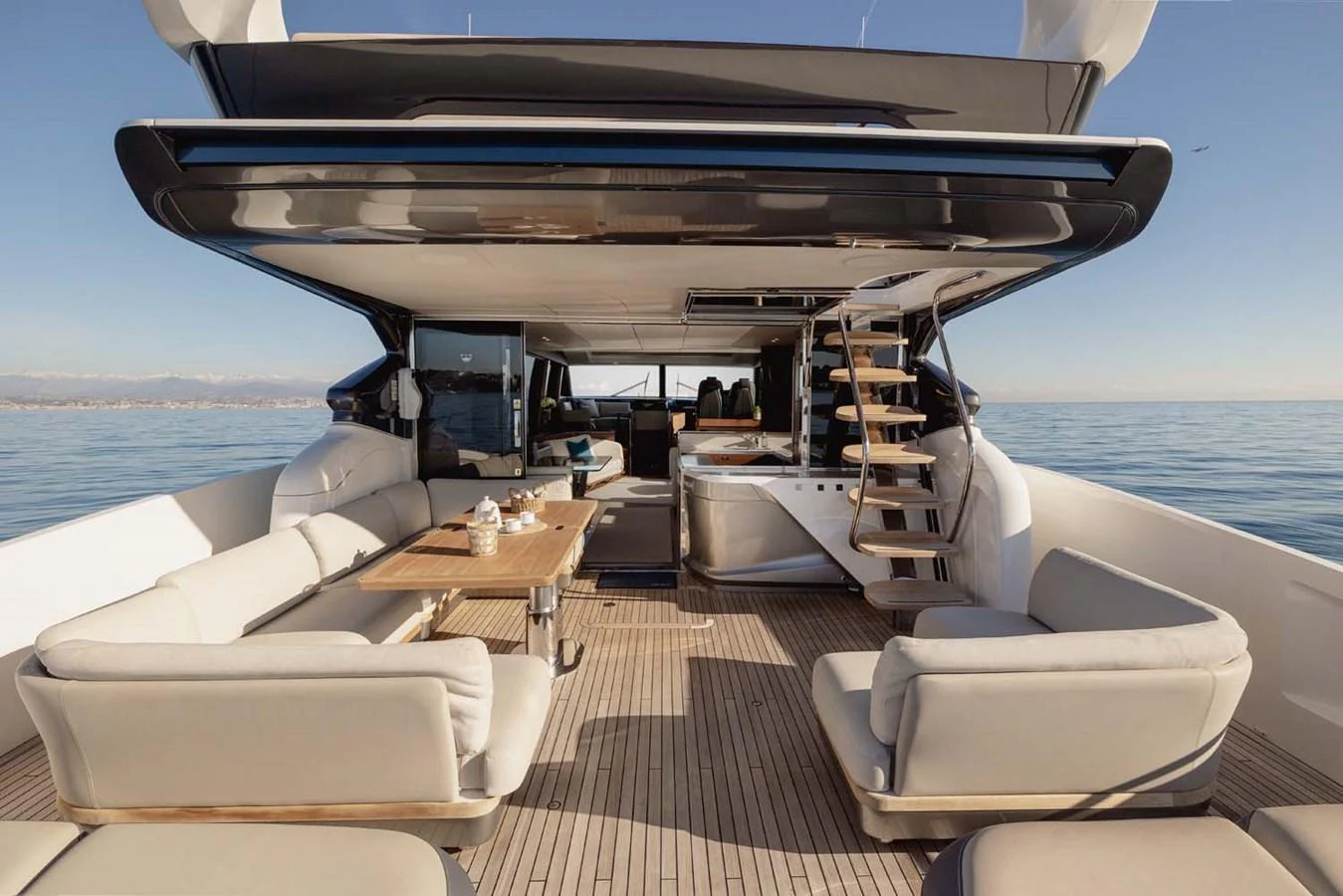 The aft deck offers a spacious and luxurious outdoor seating area with a dining table and a staircase leading to the upper deck. aboard CAMILLE Yacht for Sale