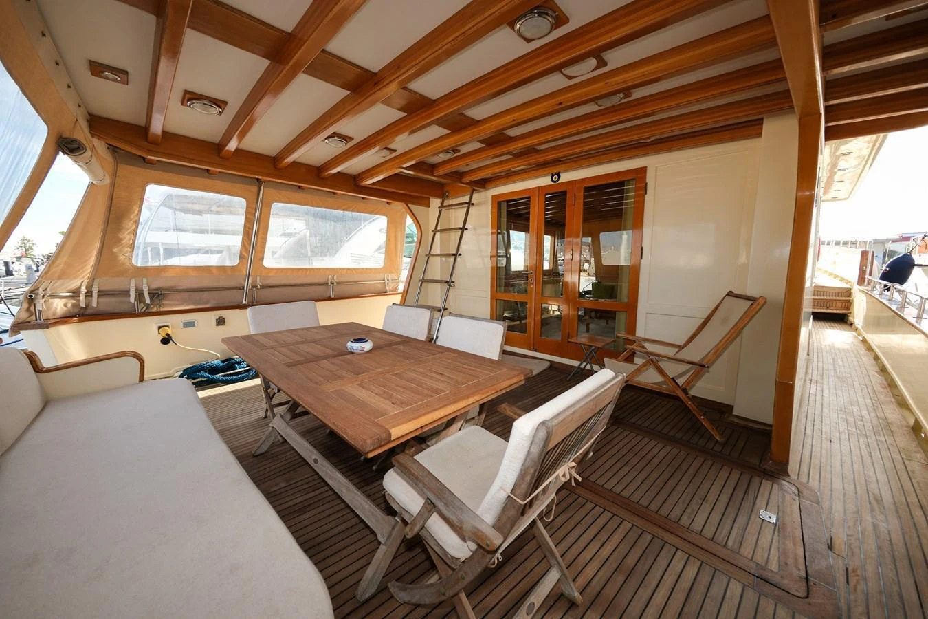 The aft deck features a comfortable seating area with a wooden table and chairs, perfect for outdoor dining and relaxation. aboard XANAX Yacht for Sale