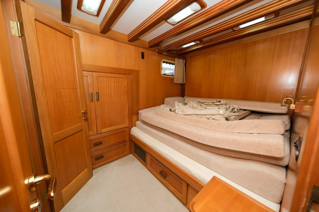 A cozy cabin with wooden paneling and neatly arranged bedding. aboard XANAX Yacht for Sale