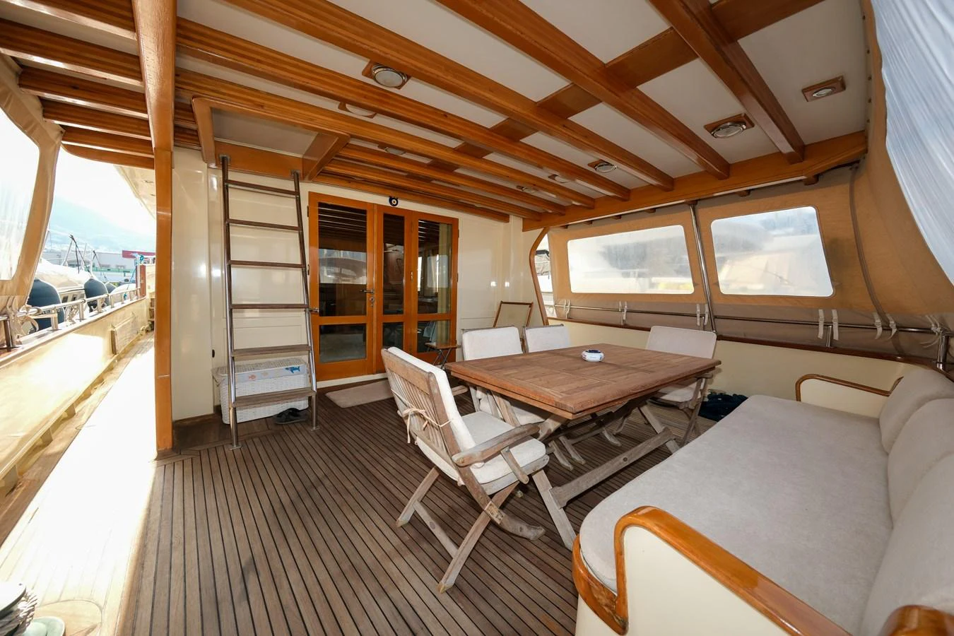 The aft deck features a comfortable dining area with a wooden table and cushioned seating, perfect for alfresco meals. aboard XANAX Yacht for Sale