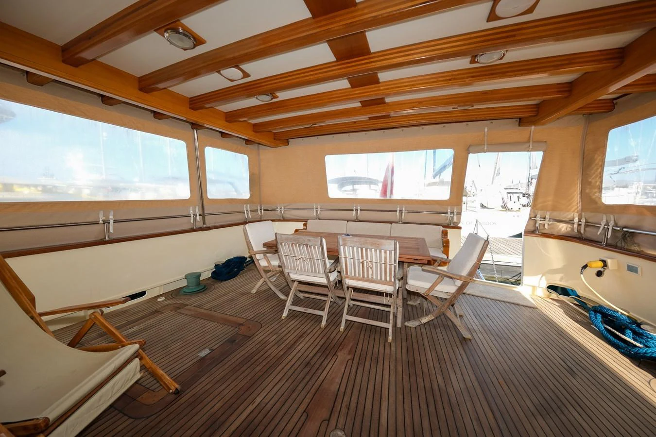 The aft deck features a cozy seating area with wooden chairs and a table, perfect for outdoor dining. aboard XANAX Yacht for Sale