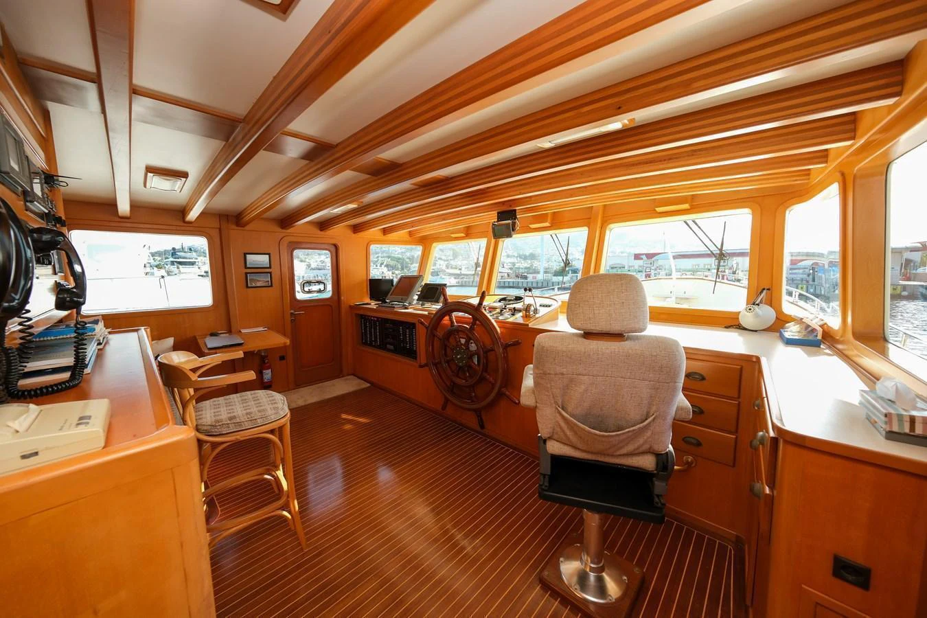 The helm station features a warm wooden interior with ample natural light and modern navigation equipment. aboard XANAX Yacht for Sale