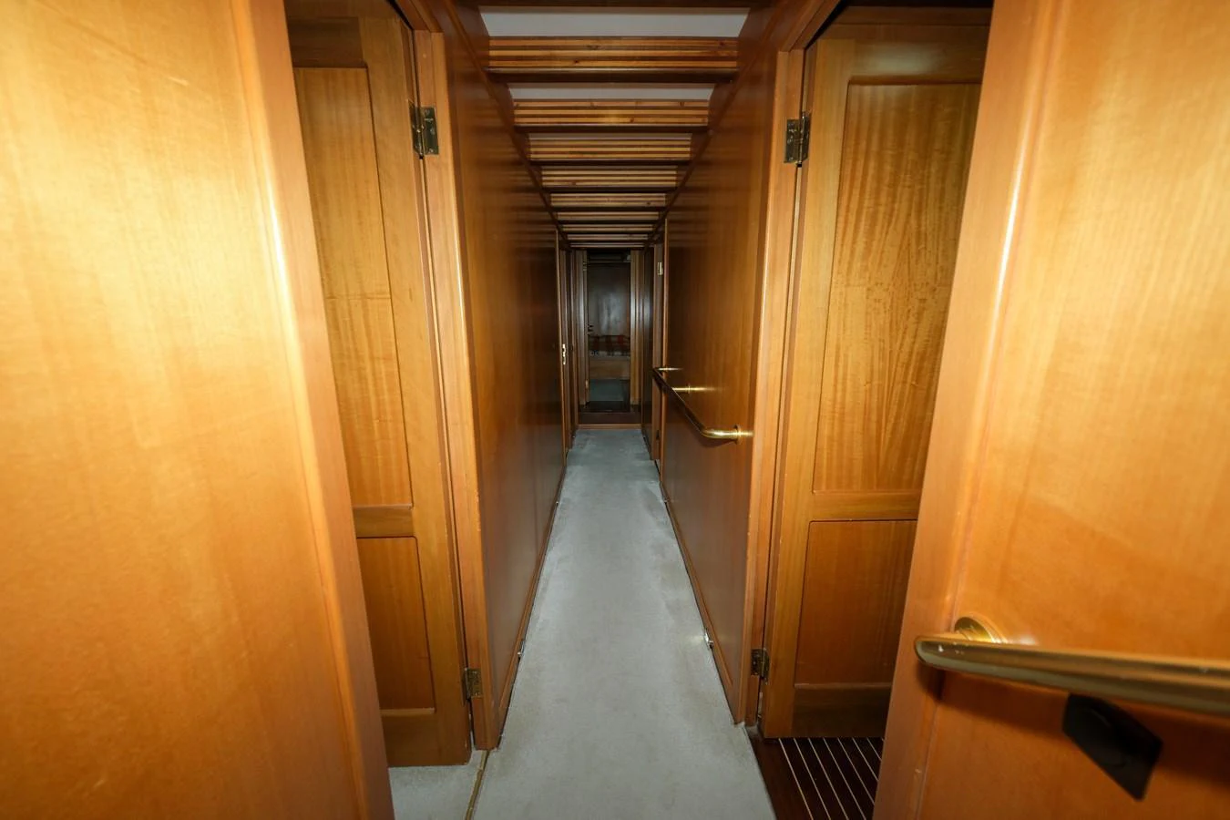 A narrow hallway with wooden doors on both sides leads to the interior of the yacht. aboard XANAX Yacht for Sale