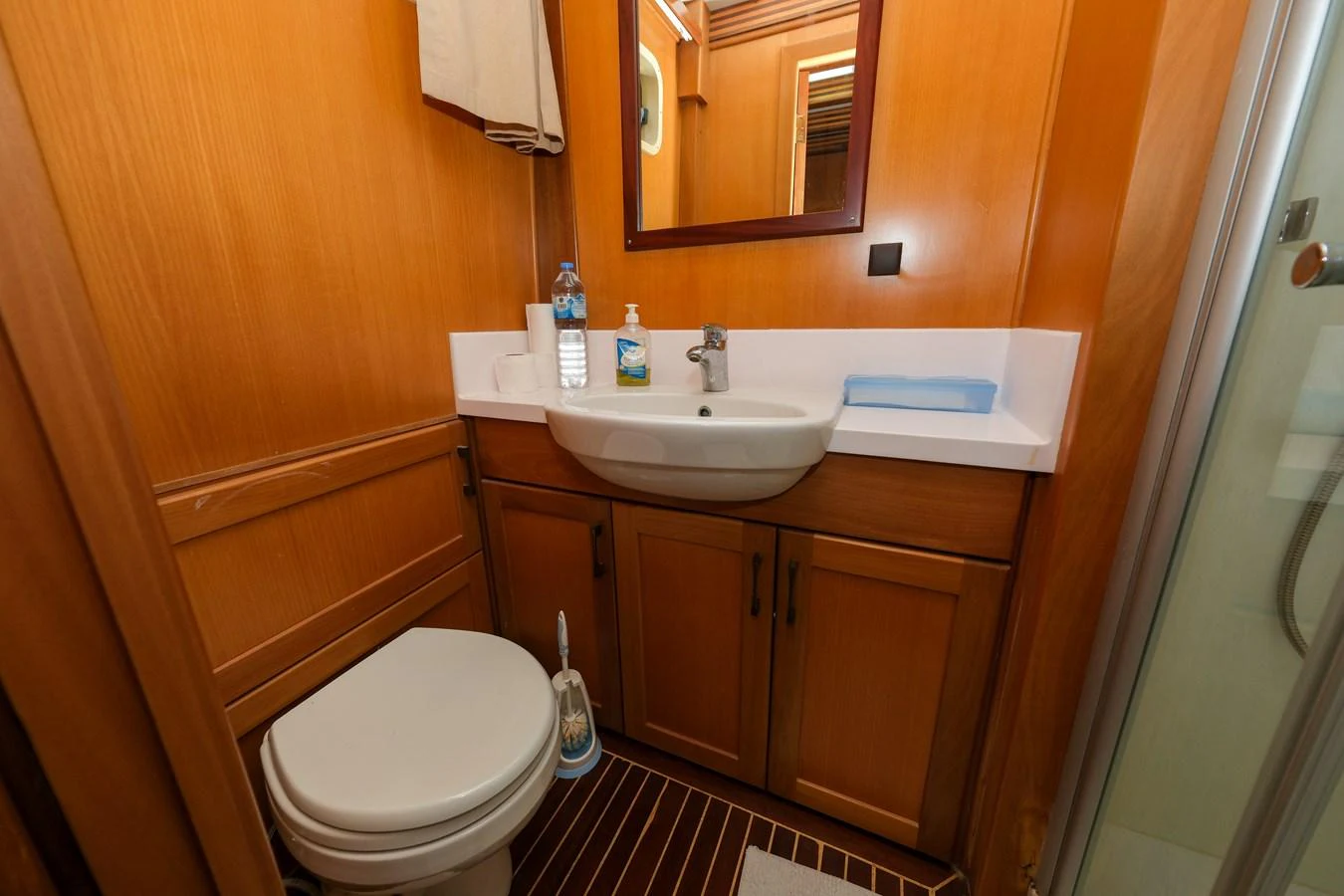 The yacht's bathroom features a sleek sink, toilet, and wooden cabinetry. aboard XANAX Yacht for Sale