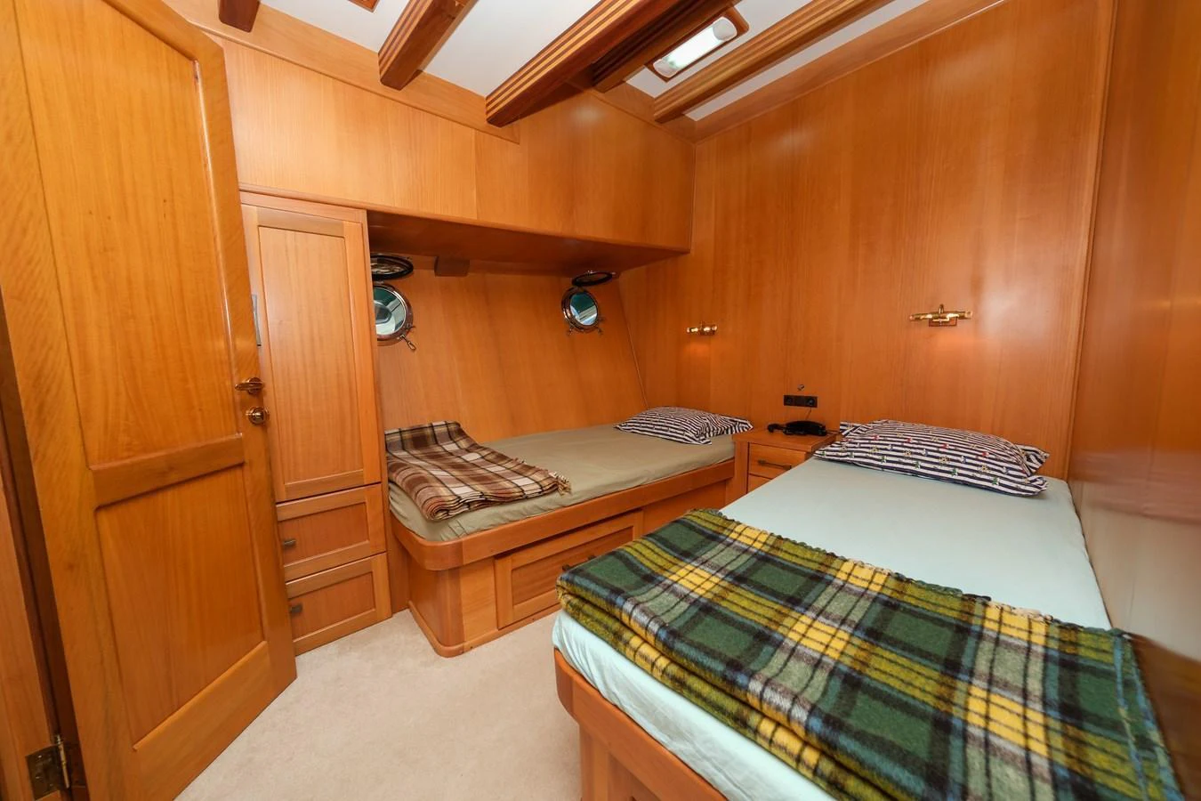 The guest cabin features twin beds with cozy bedding and warm wooden paneling. aboard XANAX Yacht for Sale