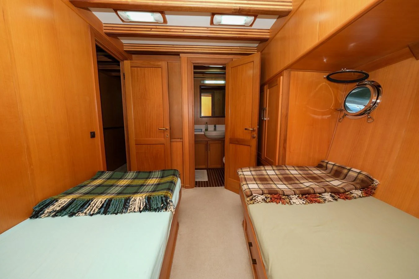 The cozy guest stateroom features twin beds with warm wooden paneling and a private ensuite bathroom. aboard XANAX Yacht for Sale