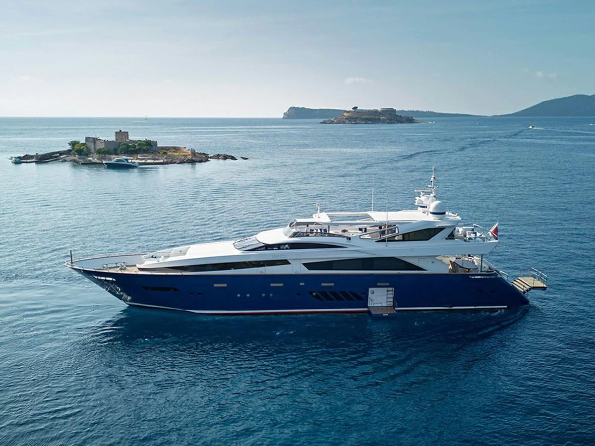 A sleek and modern yacht cruises through calm blue waters with scenic islands in the background. aboard COF Yacht for Sale