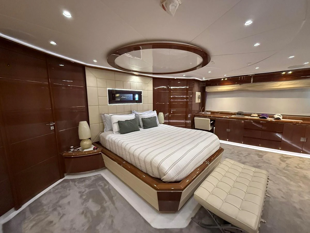 The master stateroom features luxurious wood paneling, a plush bed, and elegant lighting. aboard COF Yacht for Sale