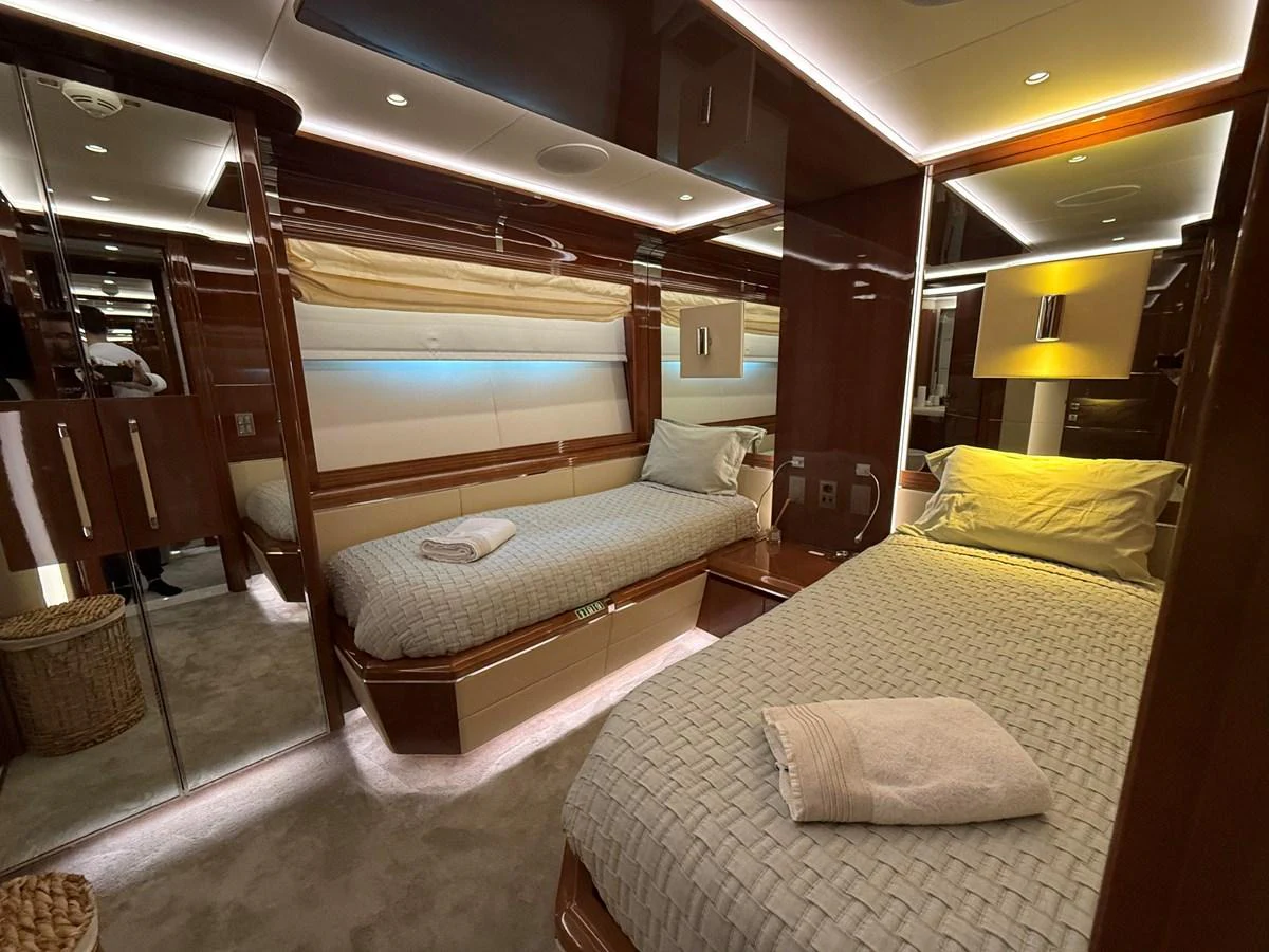 The guest stateroom features twin beds, elegant wood finishes, and soft ambient lighting. aboard COF Yacht for Sale