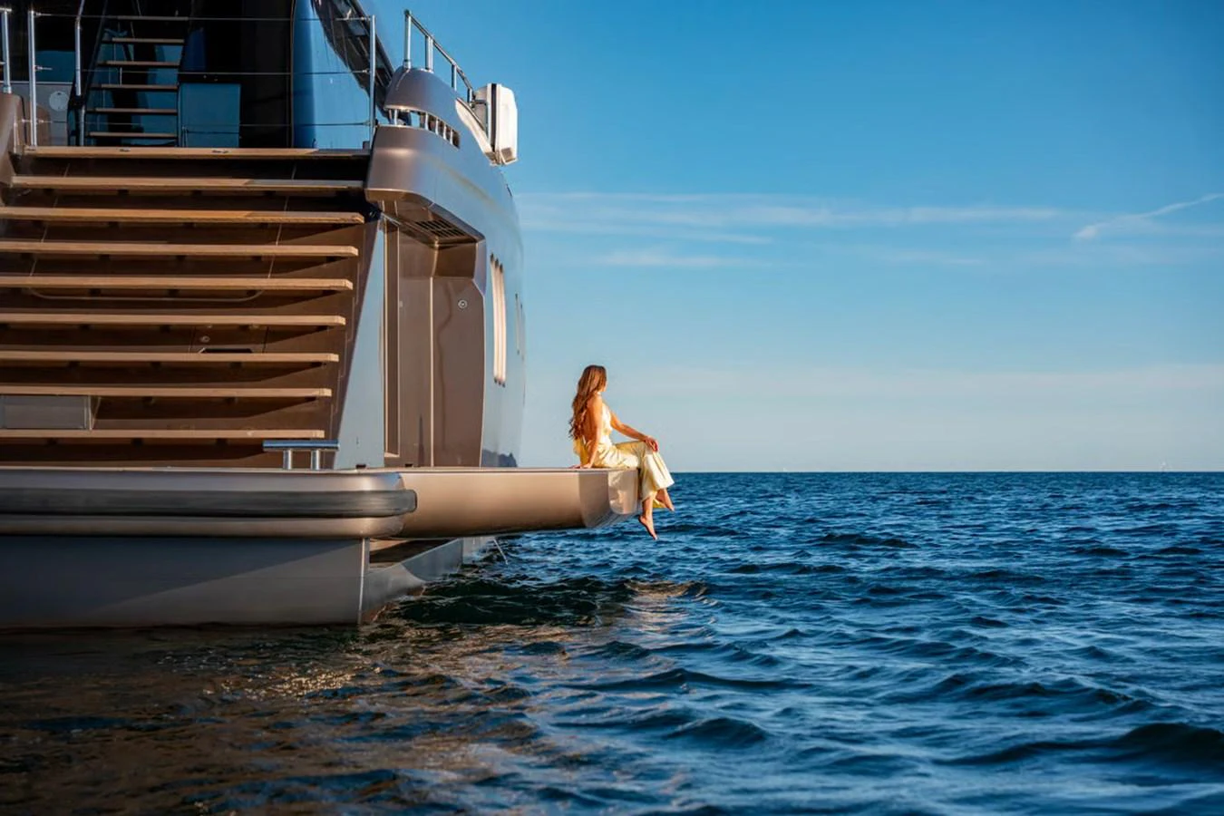 A serene moment on the aft deck of a luxurious yacht, with a woman enjoying the view over the water. aboard TWILIGHT Yacht for Sale