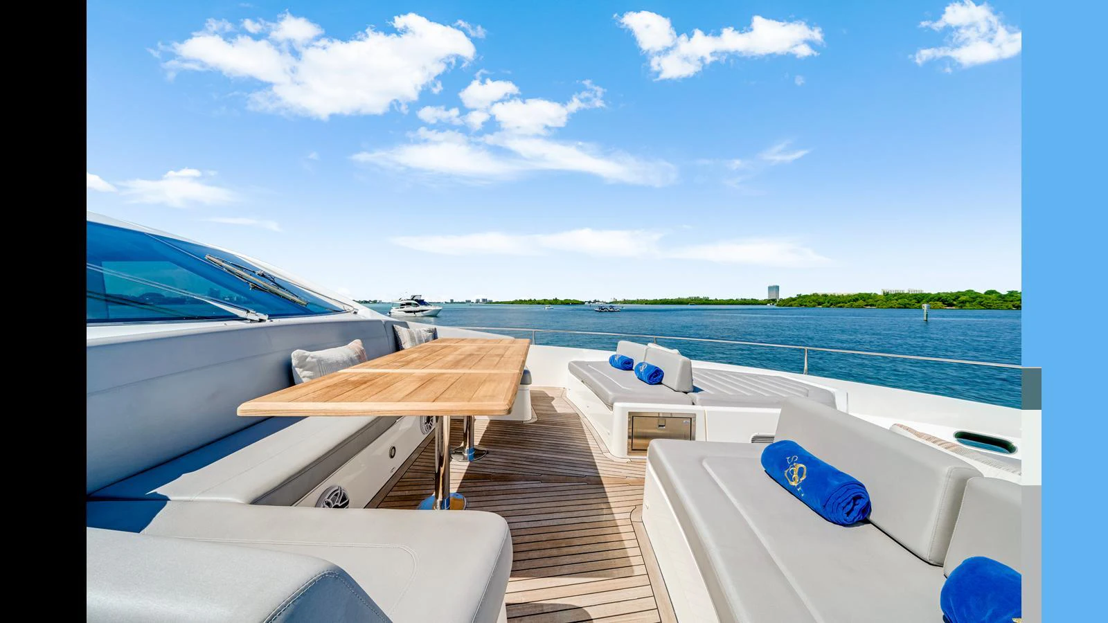 The aft deck features comfortable seating and a wooden dining table, perfect for enjoying meals with a view of the water. aboard STEELN Yacht for Sale