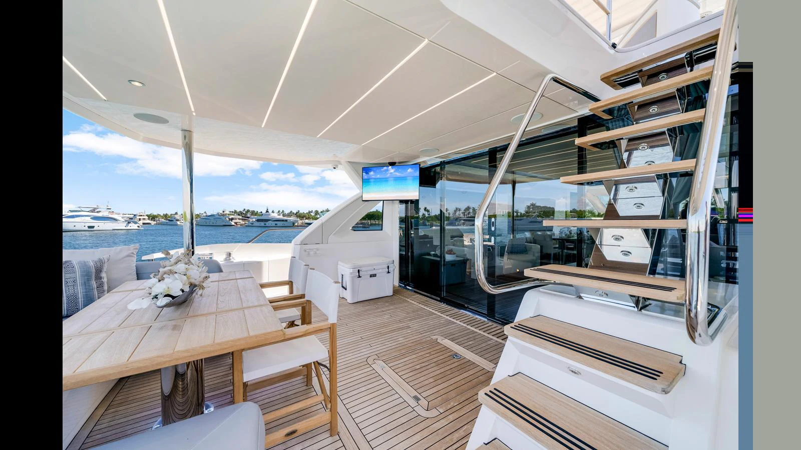 The aft deck features a spacious dining area with a view of the water, complemented by modern furnishings and a staircase leading to the upper deck. aboard STEELN Yacht for Sale