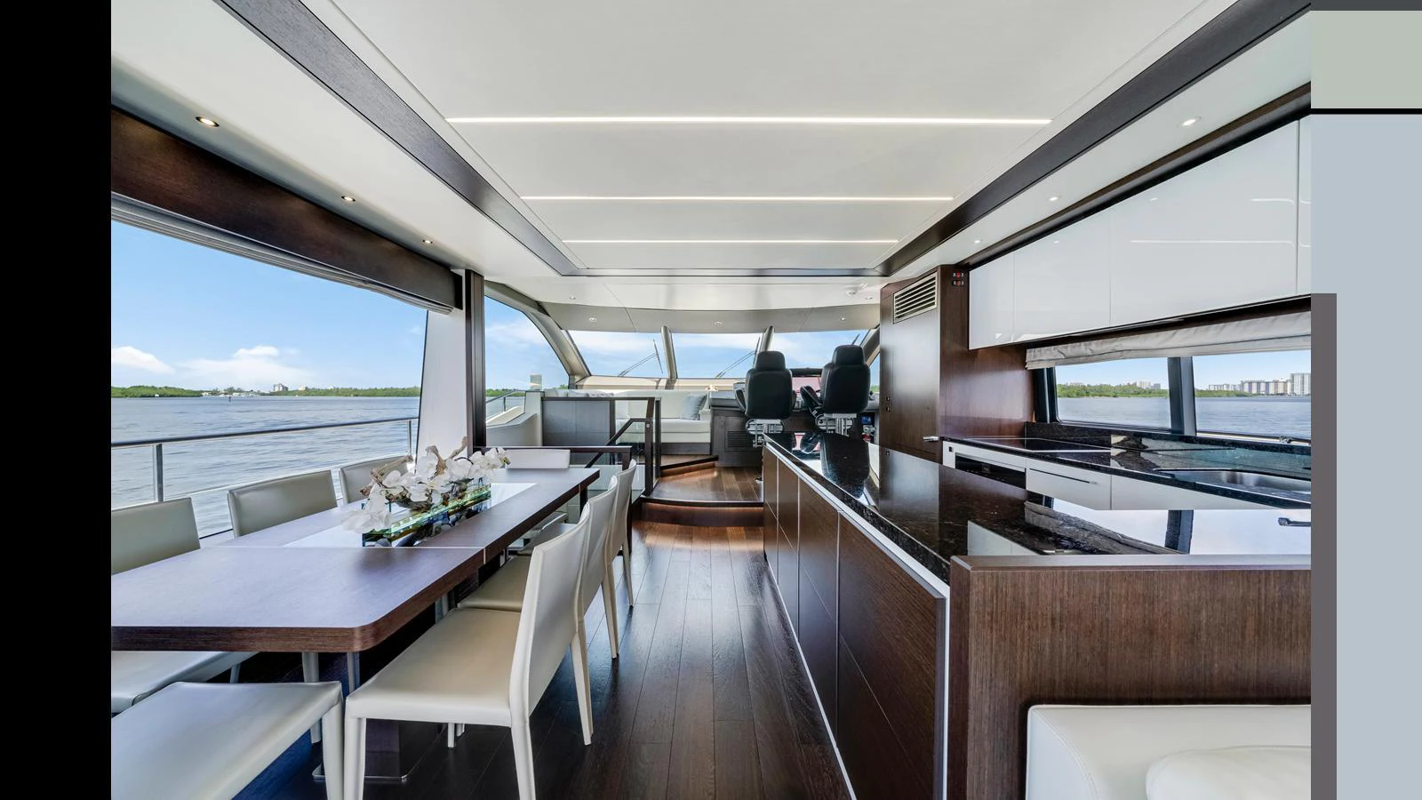The yacht's salon features a modern dining area and a sleek galley with panoramic windows offering stunning water views. aboard STEELN Yacht for Sale