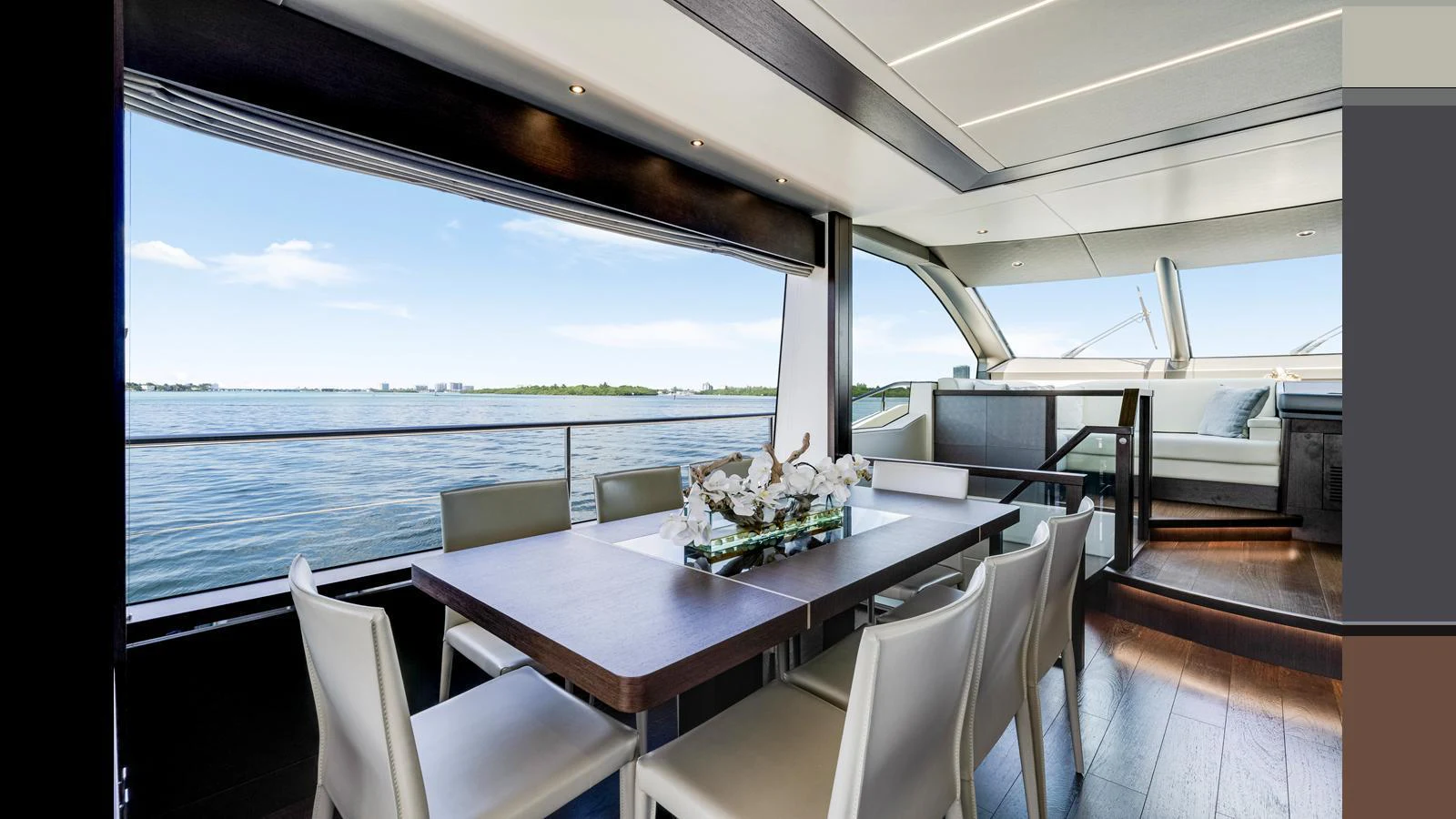 The yacht's dining area offers a stunning view of the water through large windows, complemented by modern furnishings. aboard STEELN Yacht for Sale