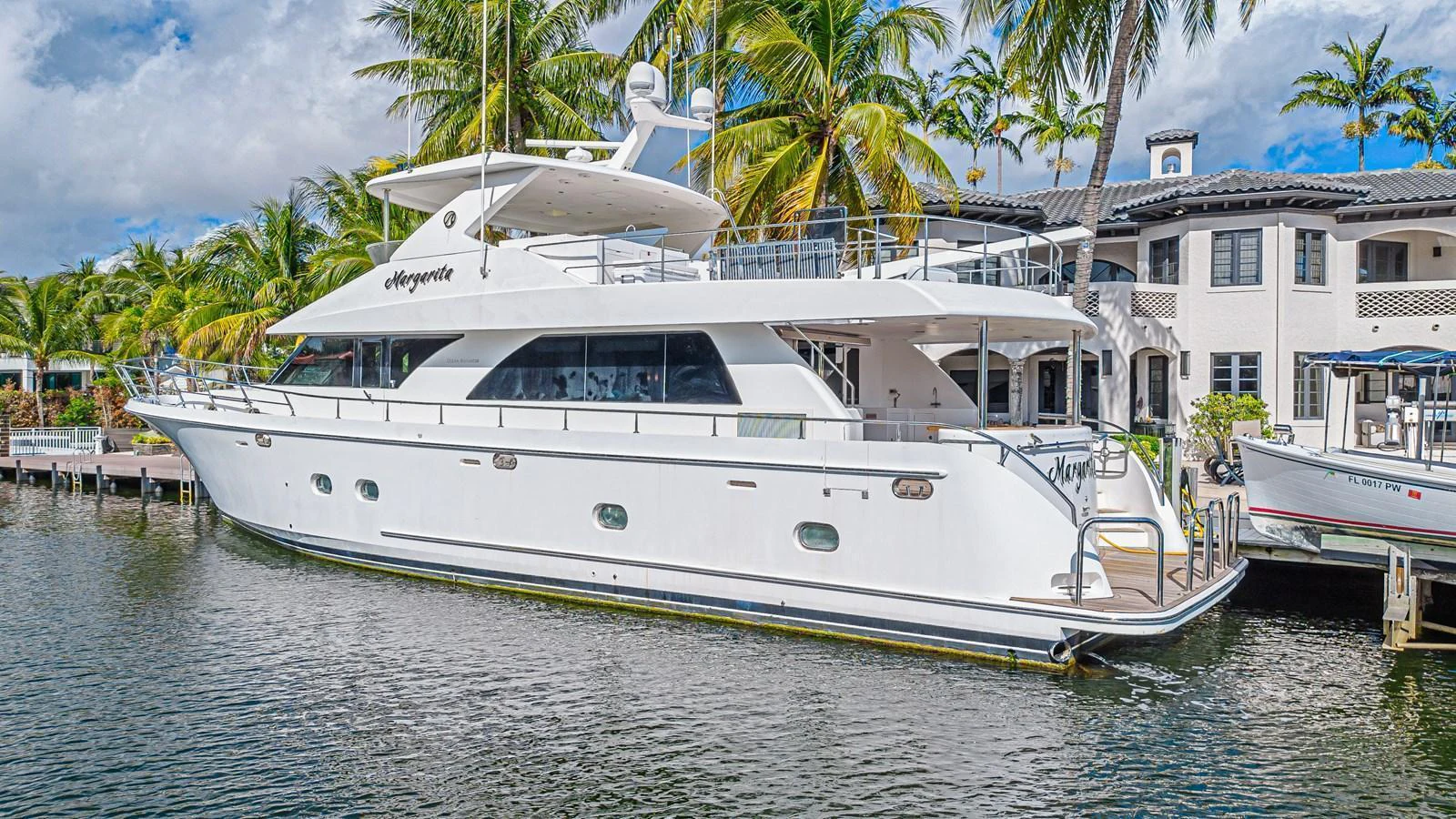 A sleek white yacht is docked in a tropical marina, showcasing its elegant design and spacious decks. aboard MARGARITA Yacht for Sale