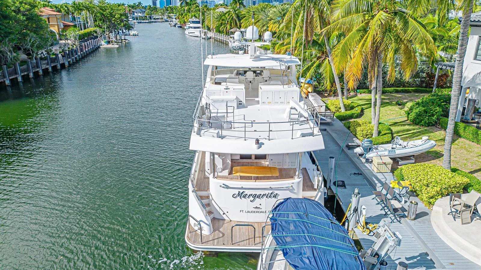 The yacht is docked in a serene canal surrounded by lush greenery and palm trees. aboard MARGARITA Yacht for Sale