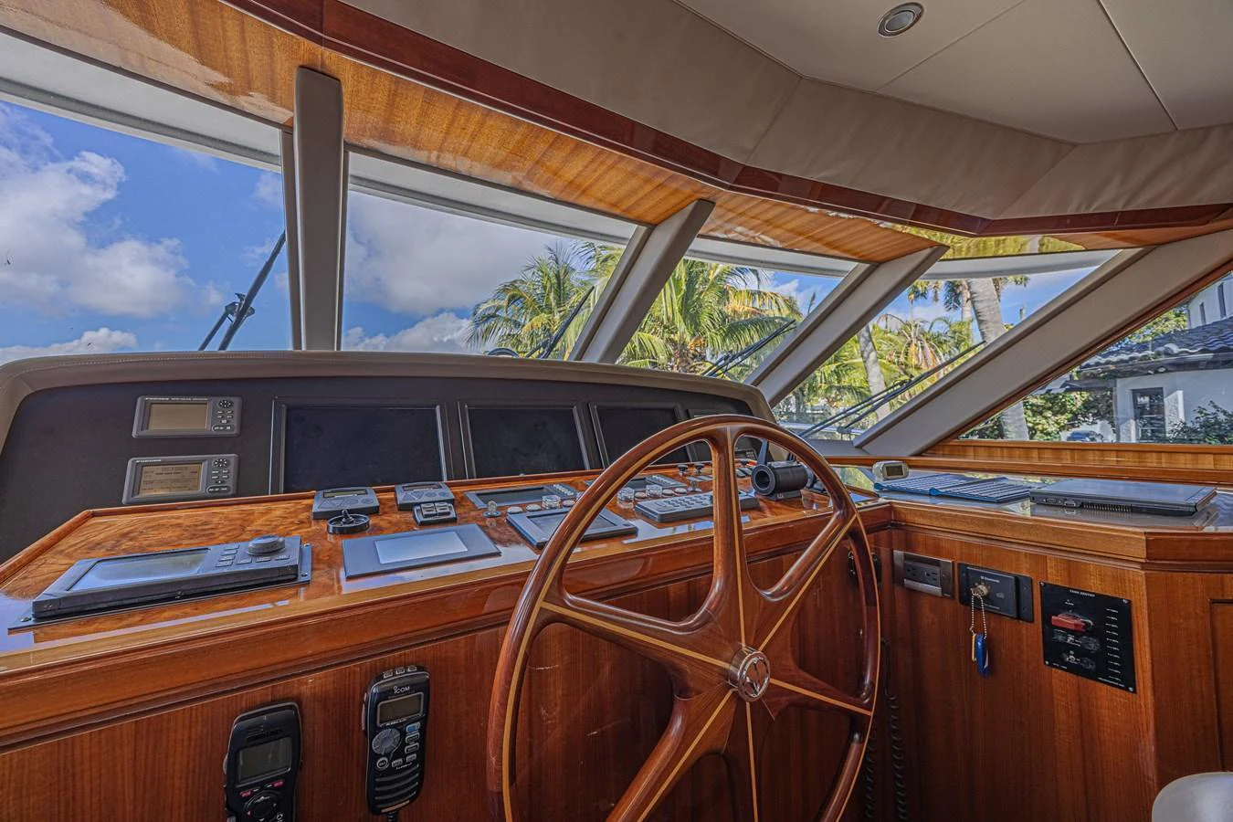 The helm station features a classic wooden steering wheel and an array of navigational instruments, set against large windows offering a scenic view. aboard MARGARITA Yacht for Sale