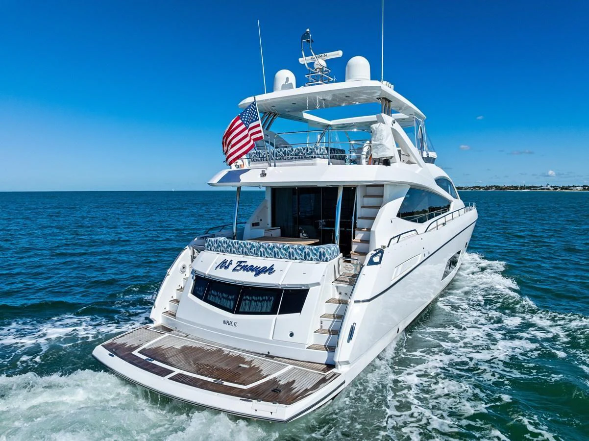 A luxurious yacht cruising on open water with a clear blue sky backdrop. aboard IT'S ENOUGH Yacht for Sale
