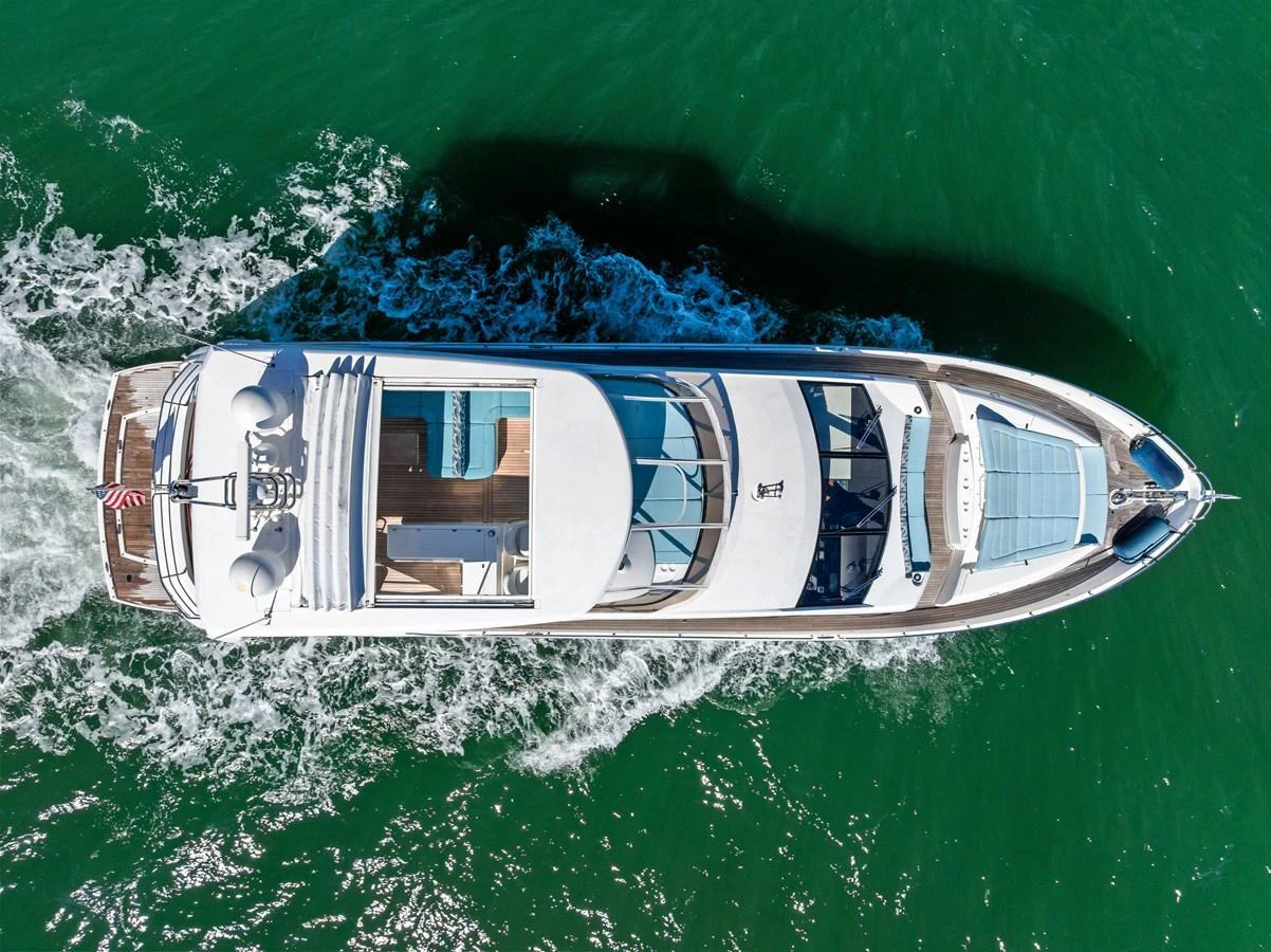 A sleek yacht cruises through vibrant green waters, showcasing its luxurious design from an aerial perspective. aboard IT'S ENOUGH Yacht for Sale
