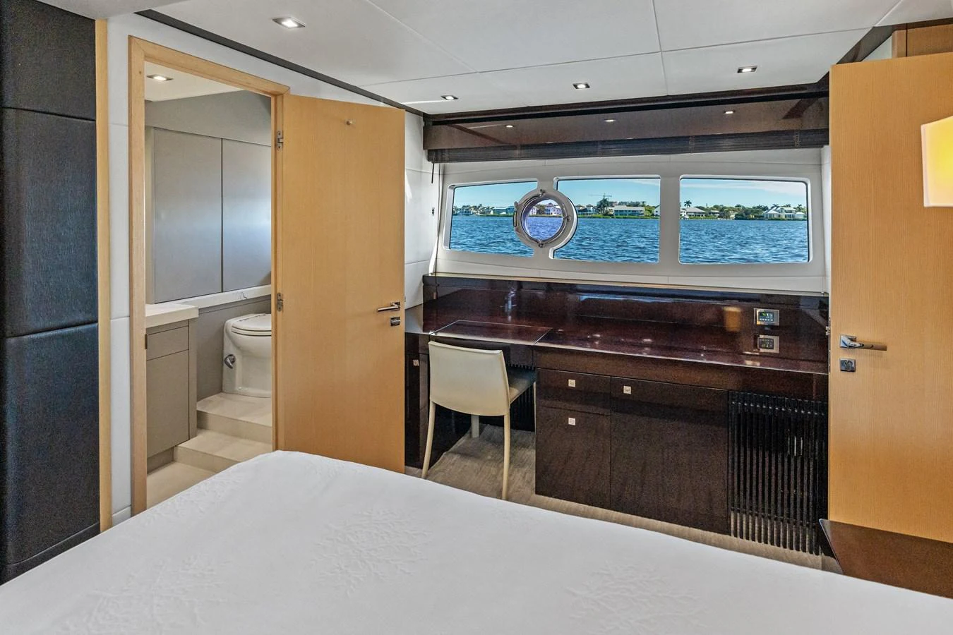 A luxurious stateroom with a view of the sea through large windows, featuring a desk and en-suite bathroom. aboard IT'S ENOUGH Yacht for Sale
