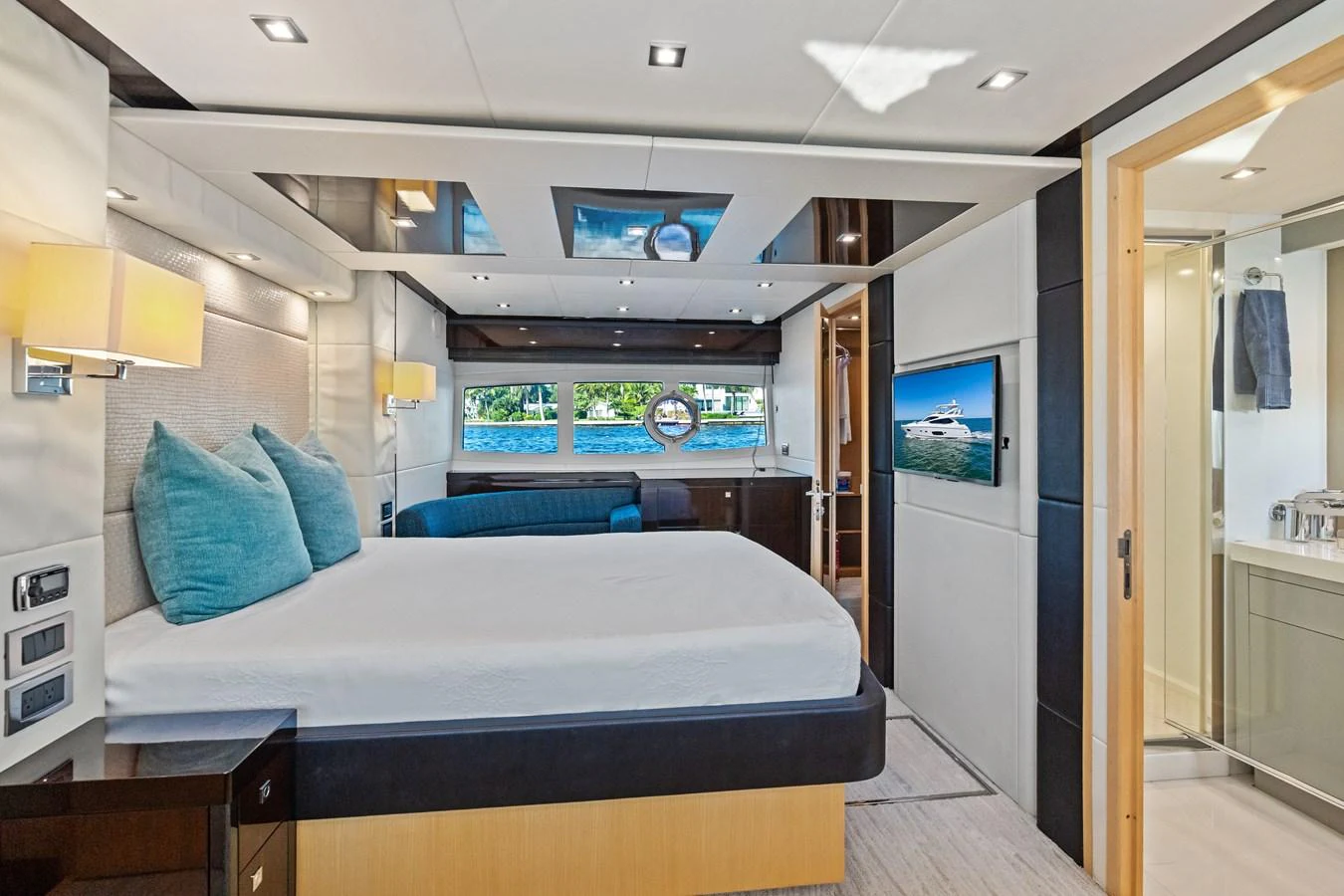 The master stateroom features a spacious bed, modern lighting, and a view of the sea through large windows. aboard IT'S ENOUGH Yacht for Sale