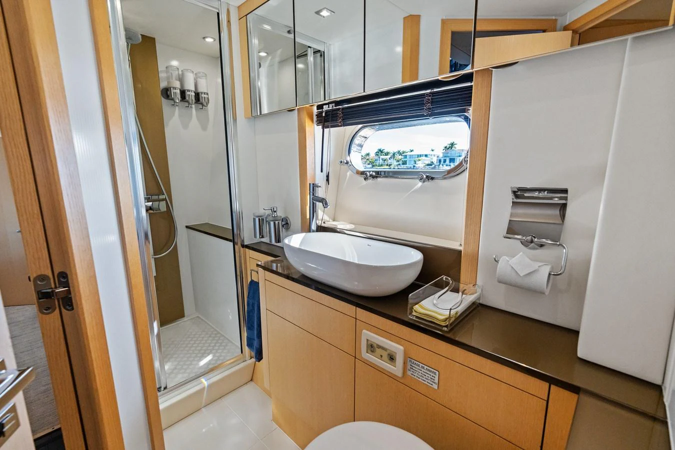 The yacht's bathroom features modern fixtures and a sleek design with a view through a porthole window. aboard IT'S ENOUGH Yacht for Sale