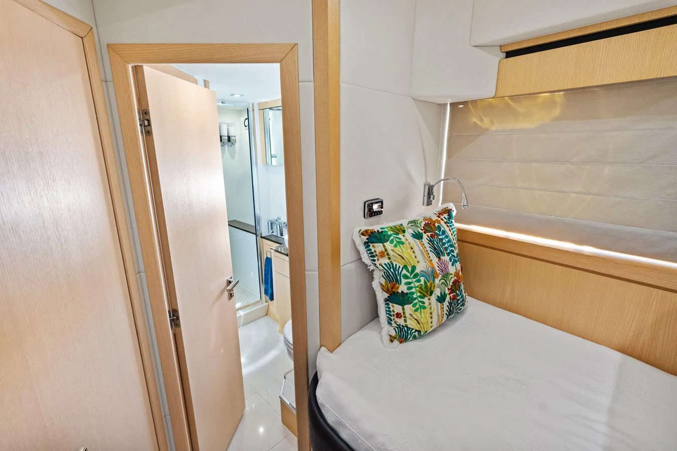 A cozy guest cabin featuring a single bed with a colorful pillow and an adjacent bathroom. aboard IT'S ENOUGH Yacht for Sale
