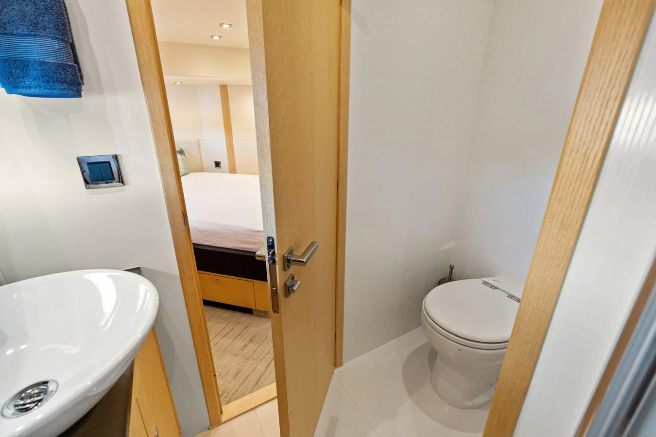 A modern yacht bathroom with a sleek sink and a view into the adjacent bedroom. aboard IT'S ENOUGH Yacht for Sale