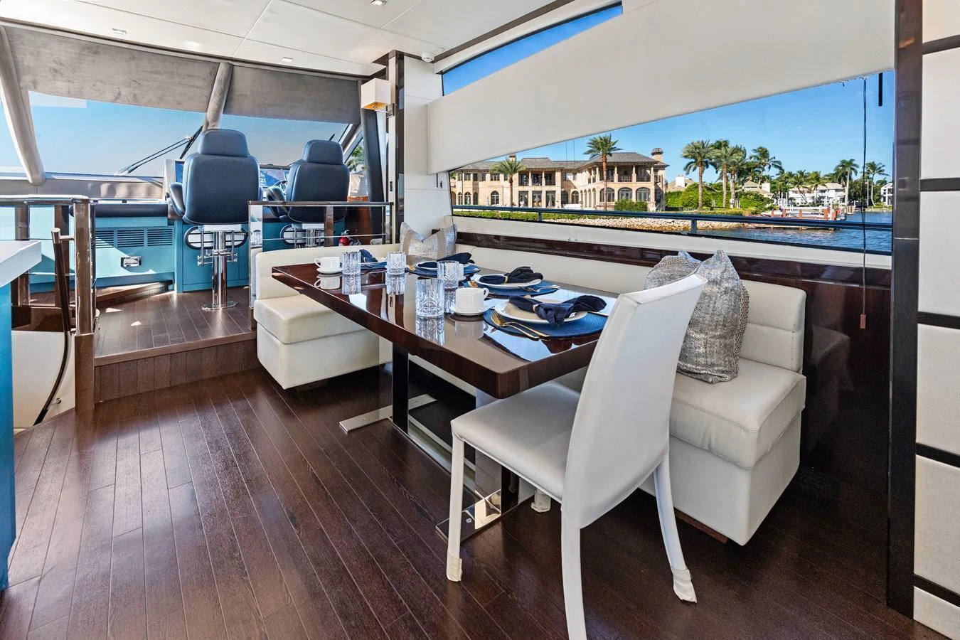 The yacht's dining area features a modern table set with elegant tableware, surrounded by comfortable seating and large windows offering scenic views. aboard IT'S ENOUGH Yacht for Sale