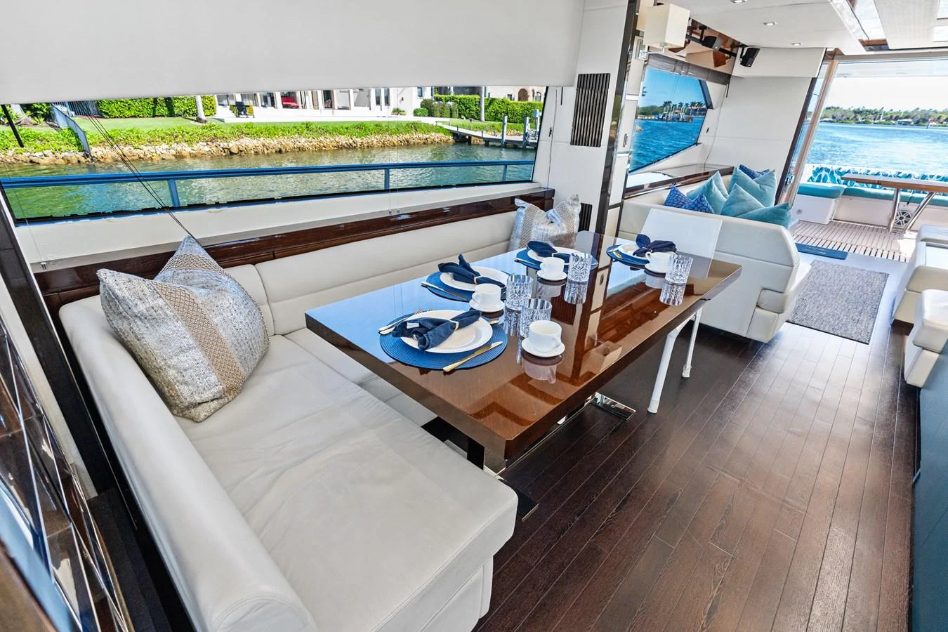 The yacht's dining area features a sleek table set for a meal, surrounded by comfortable seating and large windows offering a scenic view. aboard IT'S ENOUGH Yacht for Sale