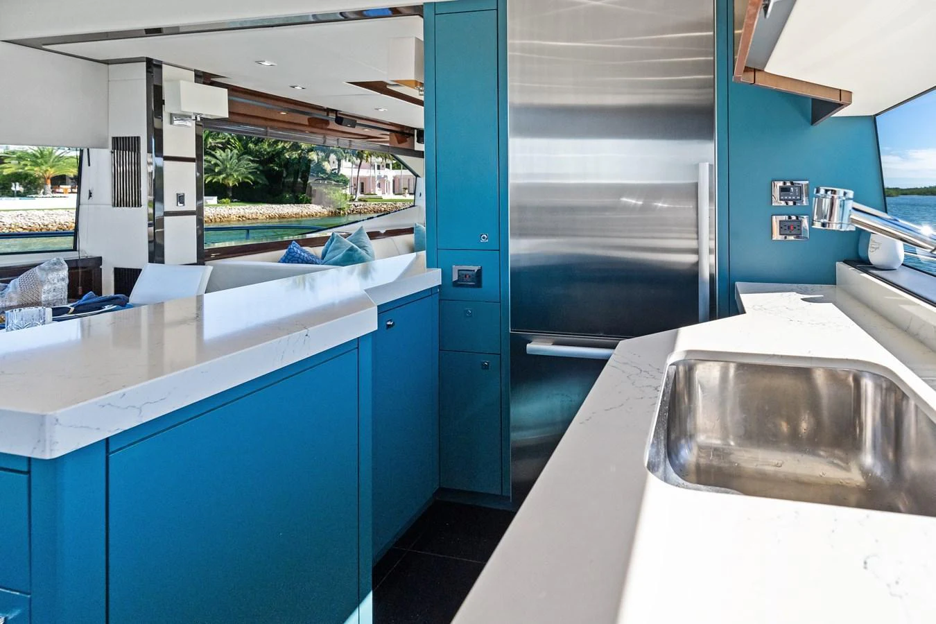 The modern galley features sleek blue cabinetry and a polished countertop with a stainless steel sink. aboard IT'S ENOUGH Yacht for Sale