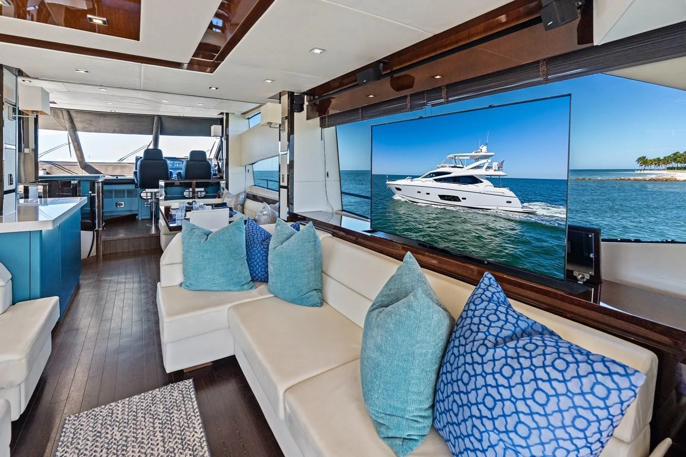The salon features plush seating with a large TV displaying a yacht, creating a luxurious and inviting atmosphere. aboard IT'S ENOUGH Yacht for Sale