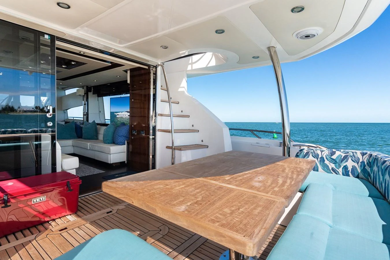 The aft deck features a spacious seating area with a wooden table, perfect for alfresco dining with a view of the sea. aboard IT'S ENOUGH Yacht for Sale