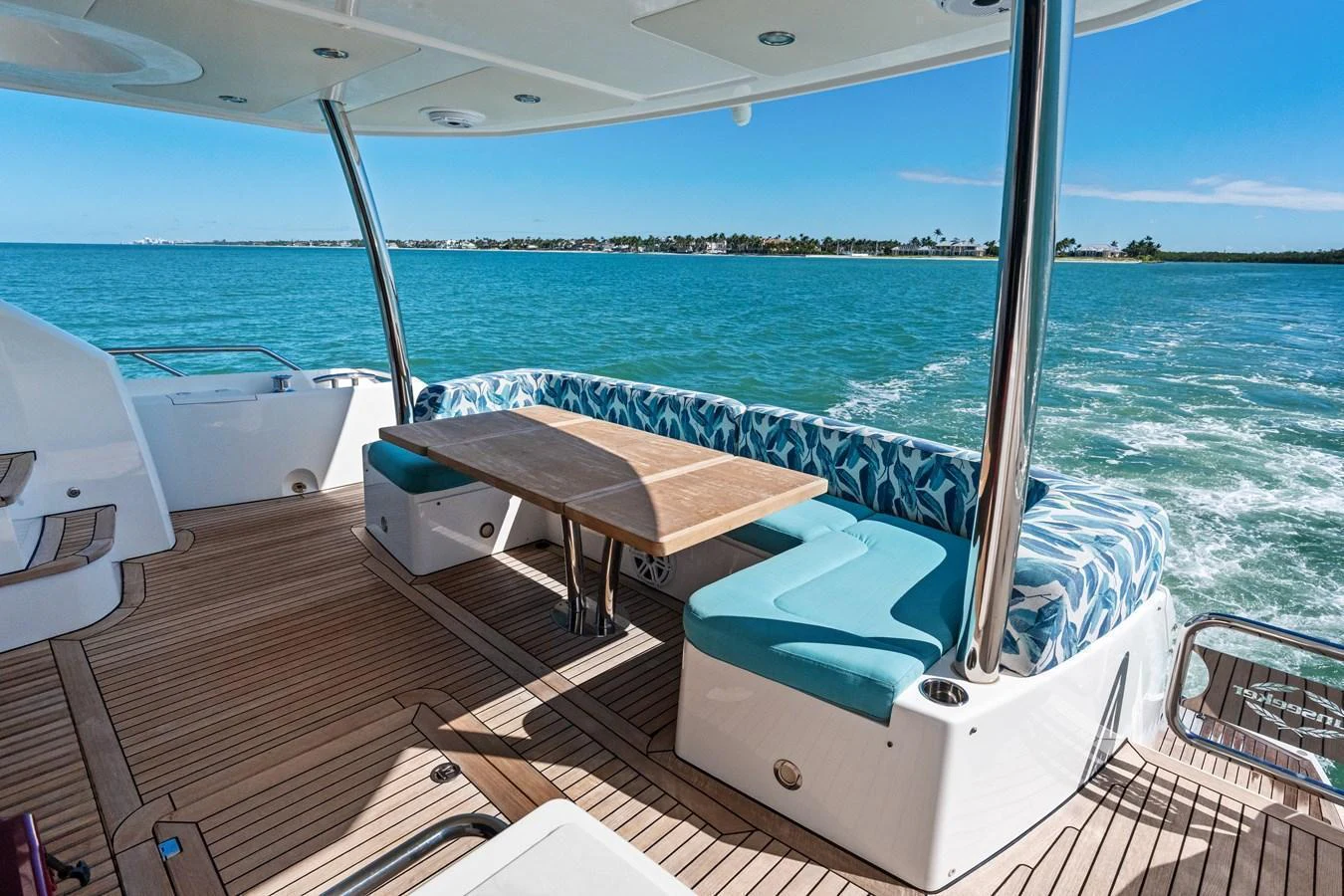 The aft deck features a spacious seating area with a wooden table, offering stunning views of the surrounding waters. aboard IT'S ENOUGH Yacht for Sale