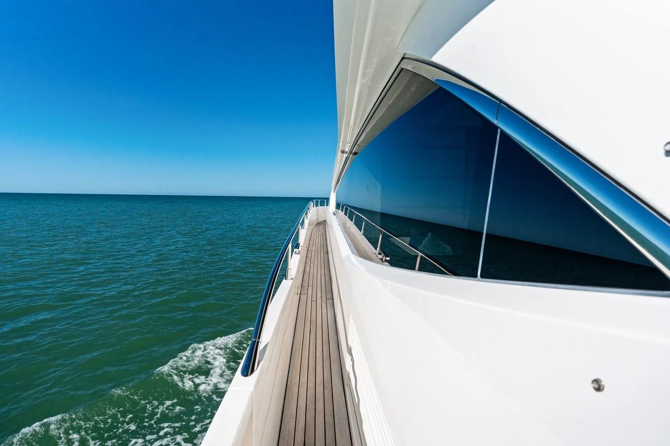 A sleek yacht cruising on calm waters with a clear blue sky. aboard IT'S ENOUGH Yacht for Sale