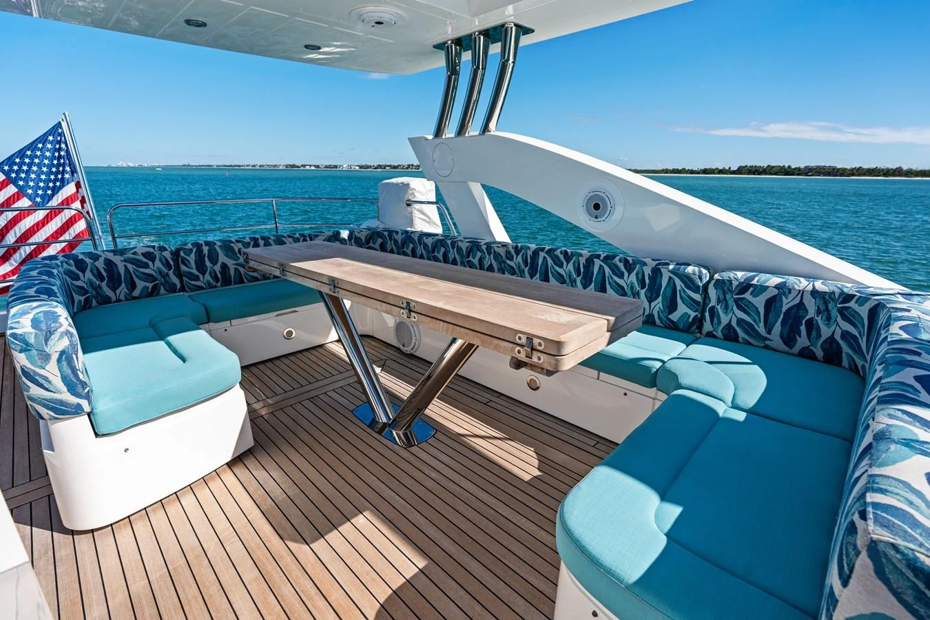 The aft deck features a spacious seating area with a wooden table, perfect for alfresco dining. aboard IT'S ENOUGH Yacht for Sale