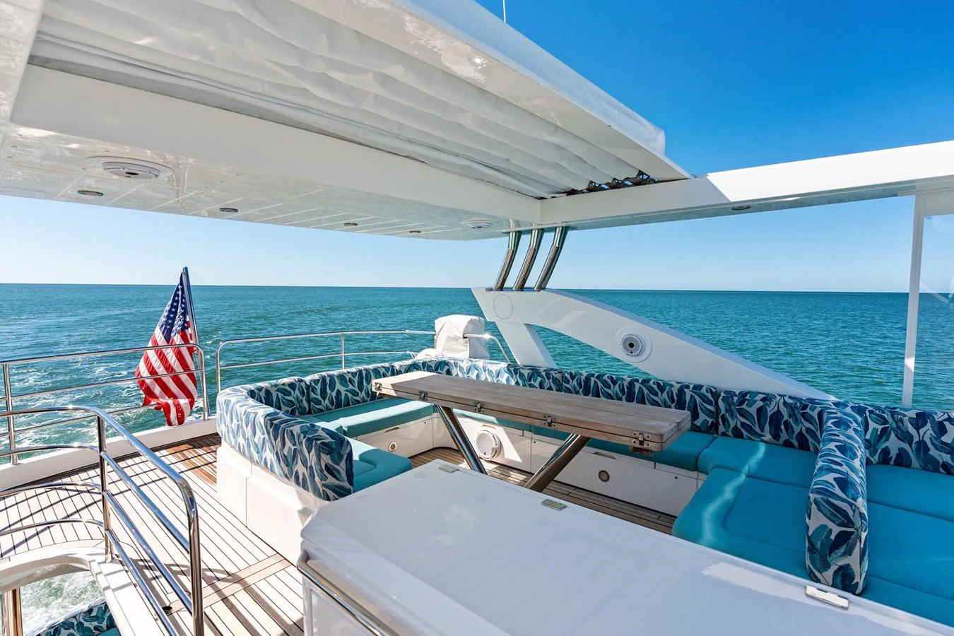 The aft deck features a spacious seating area with plush cushions and a dining table, perfect for enjoying the ocean view. aboard IT'S ENOUGH Yacht for Sale
