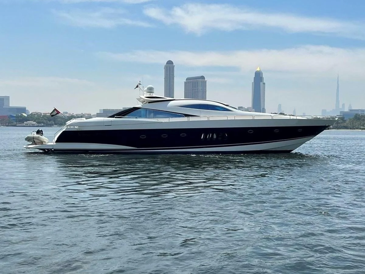 A sleek and modern yacht glides gracefully on calm waters with a cityscape in the background. aboard TIMELESS C Yacht for Sale