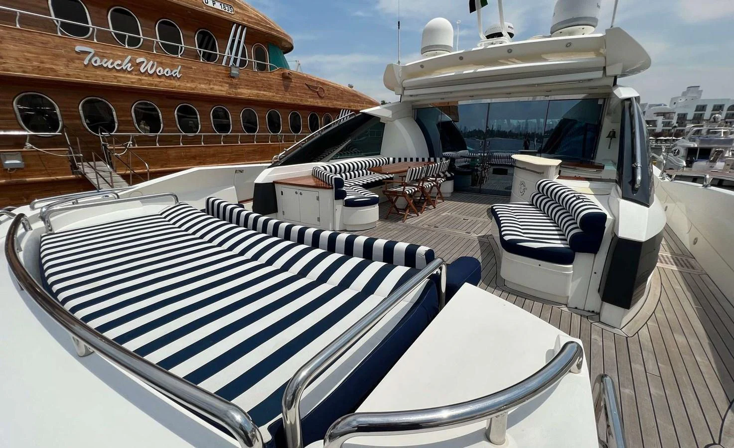 The aft deck features luxurious striped lounge seating and a spacious dining area, perfect for relaxation and socializing. aboard TIMELESS C Yacht for Sale
