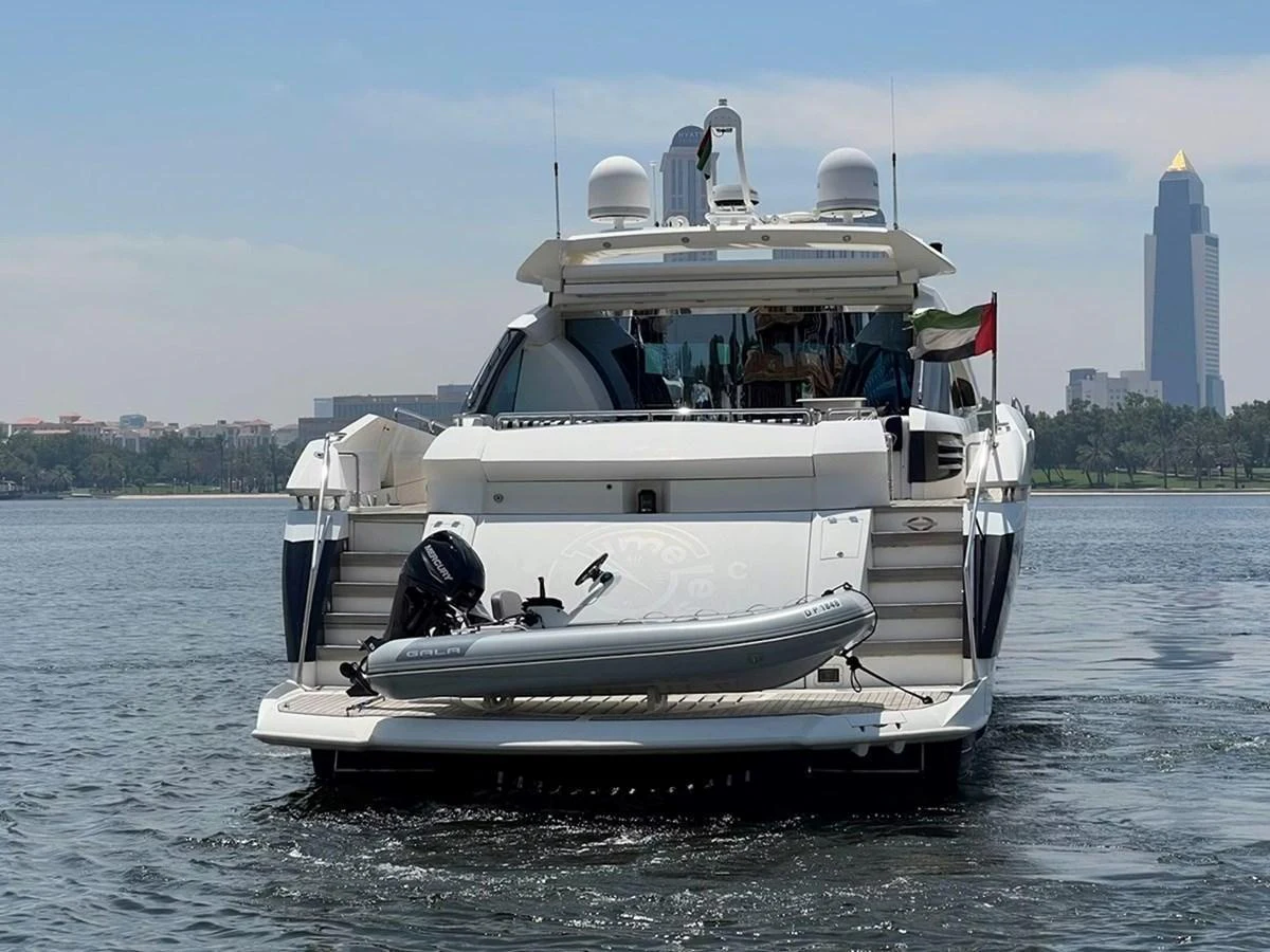 A luxurious yacht is anchored on calm waters with a cityscape in the background. aboard TIMELESS C Yacht for Sale