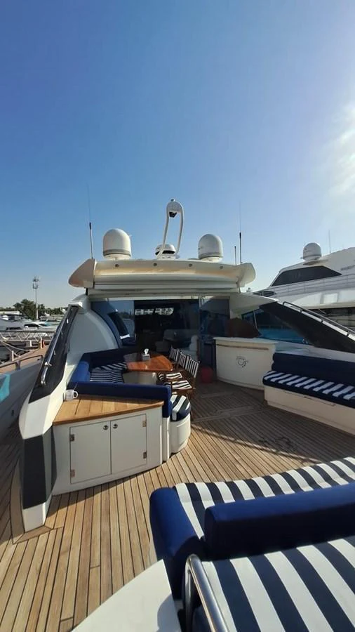 The aft deck features comfortable seating with striped cushions, a wooden table, and a sleek design. aboard TIMELESS C Yacht for Sale