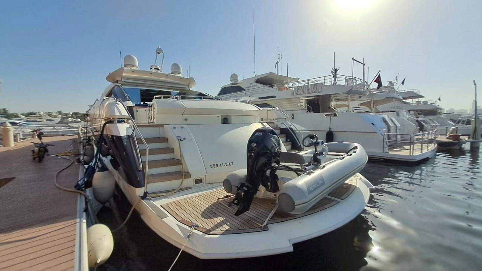 The yacht is docked at a marina, showcasing its elegant aft deck and tender. aboard TIMELESS C Yacht for Sale