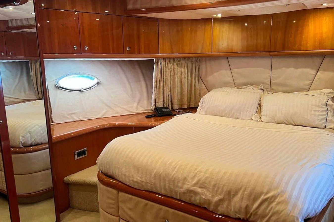 The stateroom features a luxurious bed with elegant wood paneling and ample storage space. aboard TIMELESS C Yacht for Sale