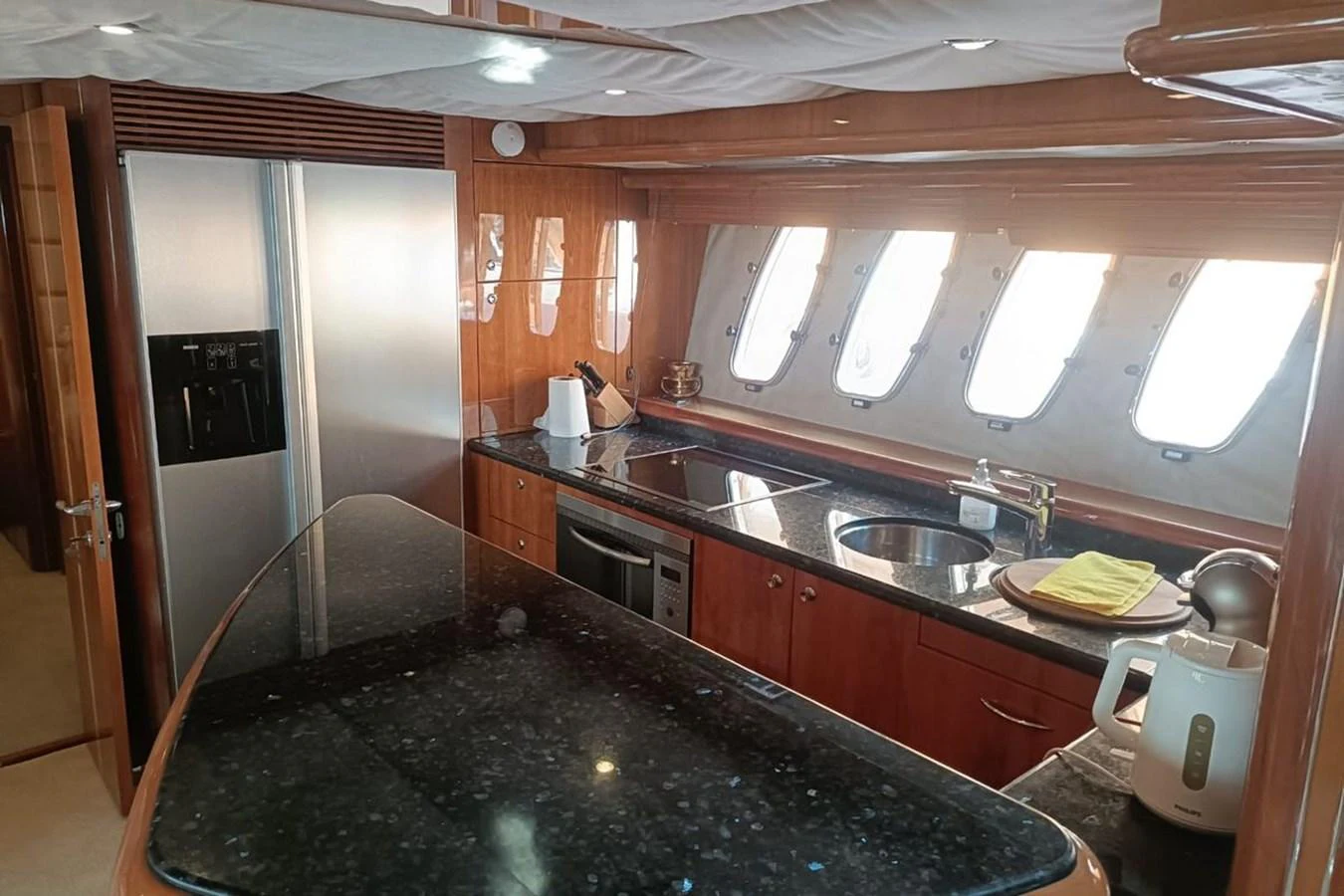 The yacht's galley features modern appliances and ample counter space, illuminated by natural light from the windows. aboard TIMELESS C Yacht for Sale
